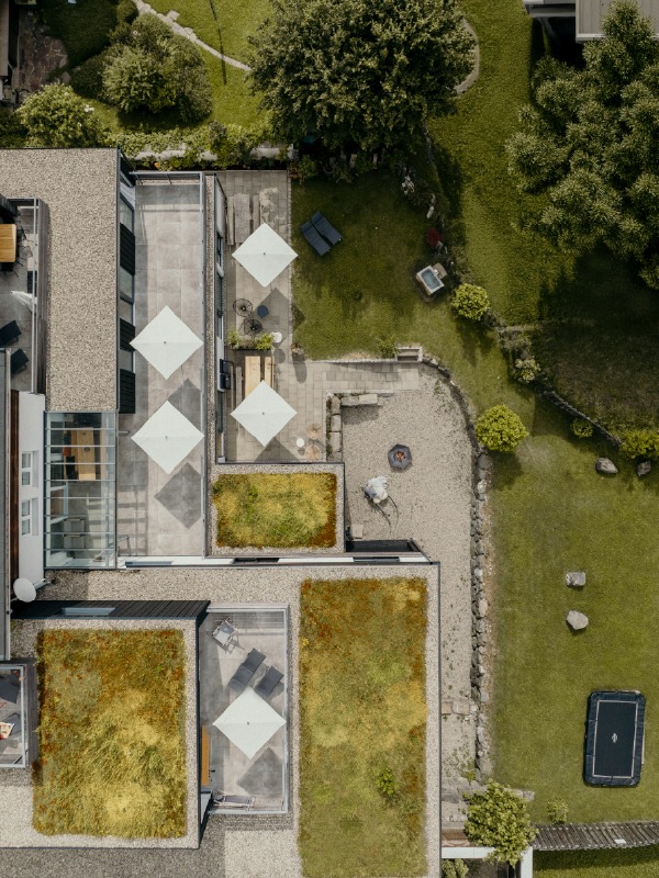 Luftaufnahme eines modernen Gebäudes mit begrünten Dächern, Terrassen und Gartenbereich.